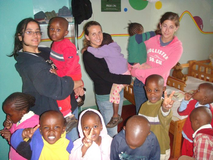 volunteers carrying and surrounded by kids