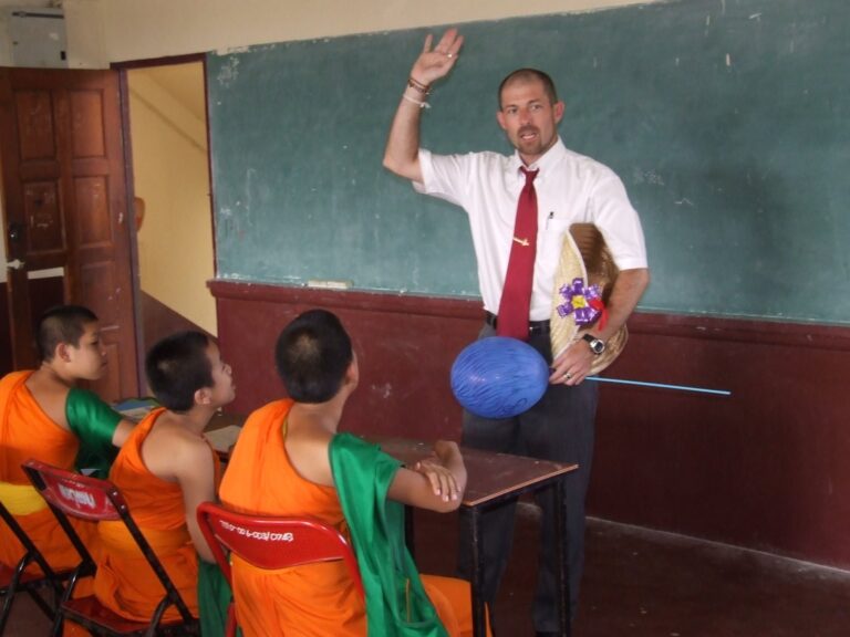 A volunteer teaching English to young novice monks in a temple-school classroom in Chiang Mai, Thailand