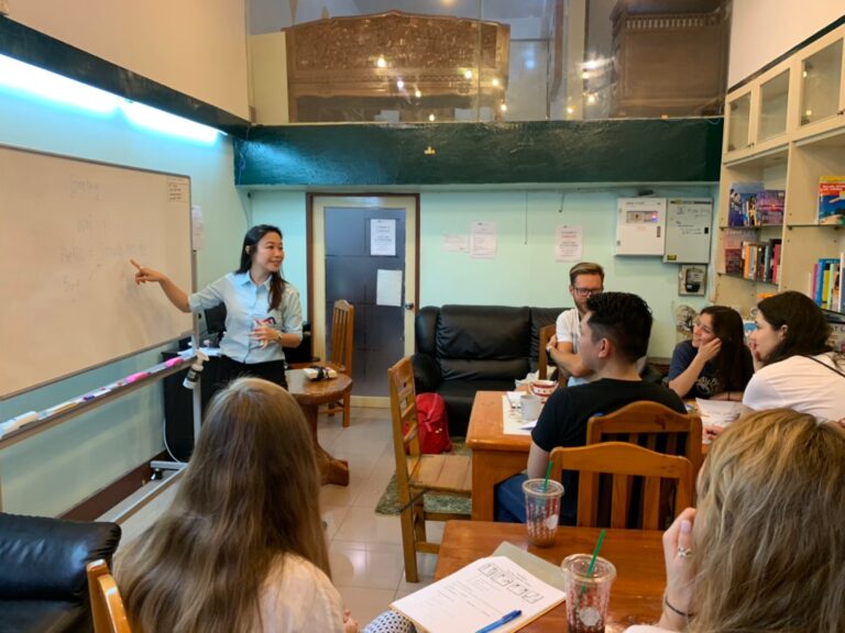 Local coordinator giving a student volunteer group an orientation briefing at a whiteboard