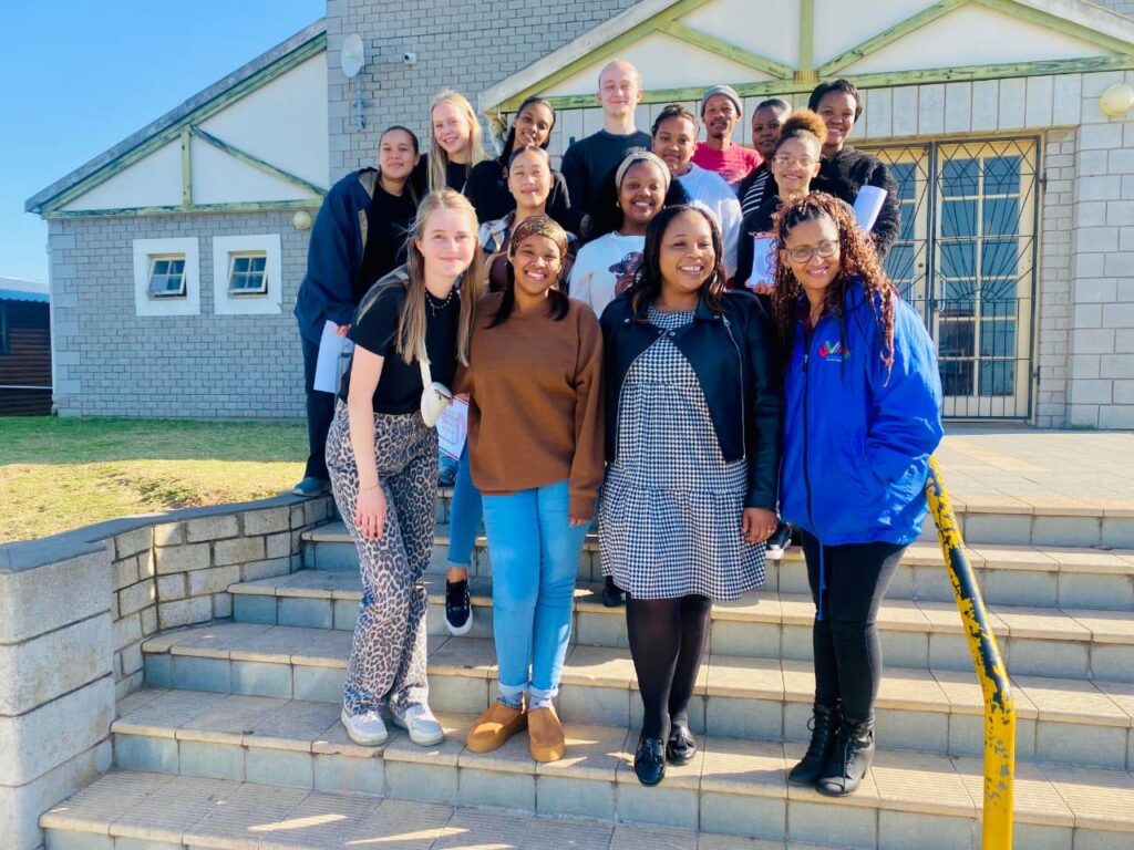 A group of student volunteers gathered on the steps of a community project building in Port Elizabeth, South Africa