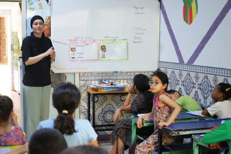 Volunteer leading a class in a community centre in Rabat, with French vocabulary on the whiteboard