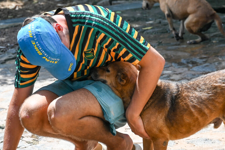 Volunteer crouching to comfort a rescued street dog at the dog care project in southern Sri Lanka