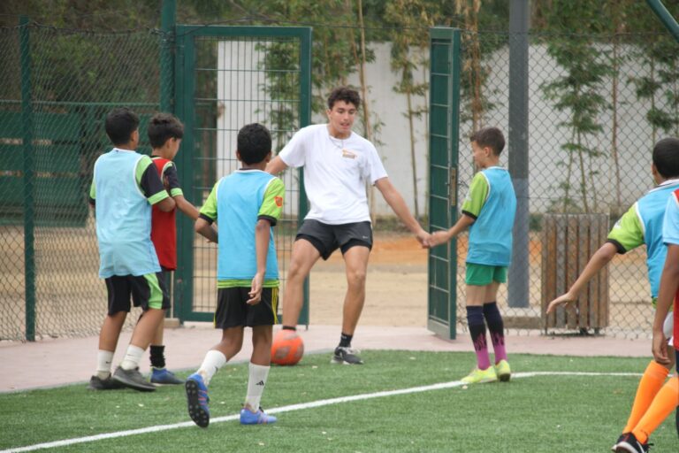 Volunteer running a football session with teenage boys on a pitch in Rabat, Morocco