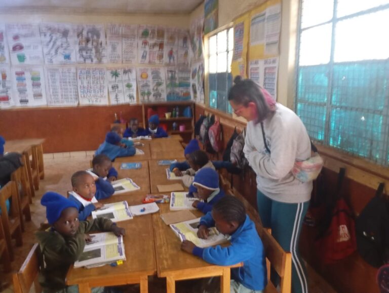 Volunteer helping primary-school children with their workbooks in a classroom