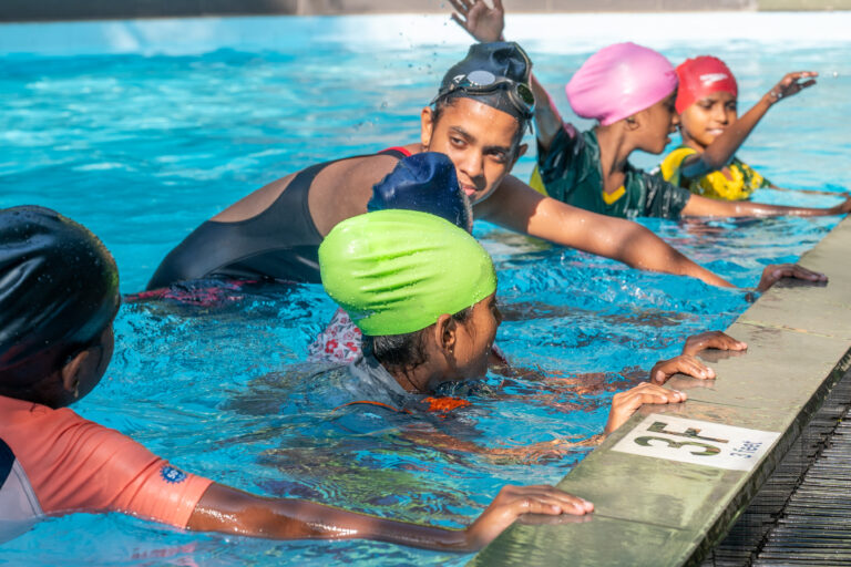 A swimming instructor teaching children to float at the poolside during the Sri Lanka sports coaching programme