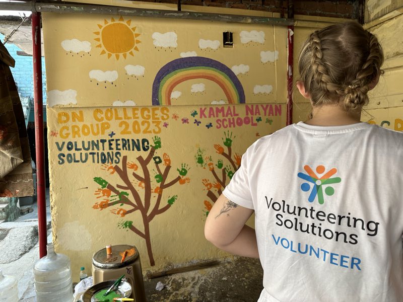 A volunteer beside a finished school mural