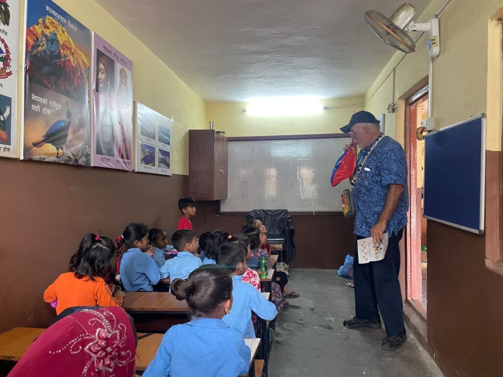 Older volunteer teaching a class of young children at a partner school