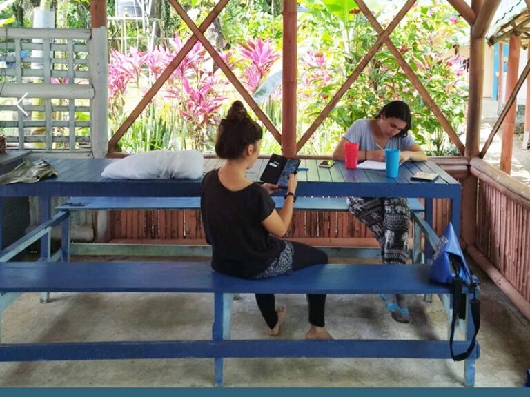 Volunteers reading and writing at the open-air shelter of a turtle conservation camp in Costa Rica